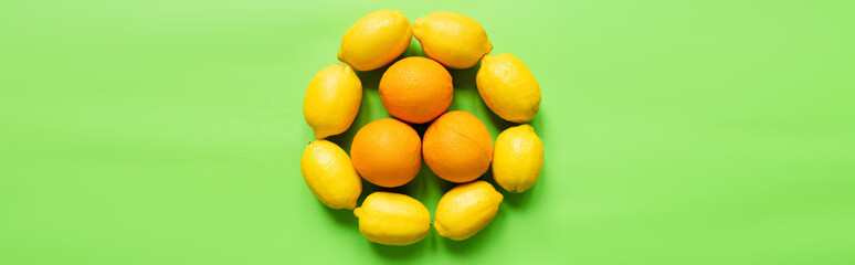 top view of ripe lemons and oranges arranged in circle on green background, panoramic orientation