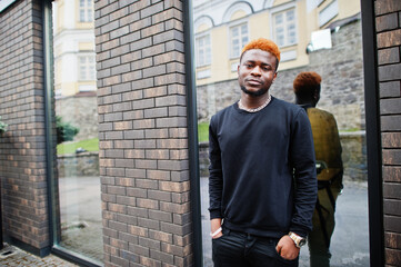 African red haired man wear black outfit posing outdoor.
