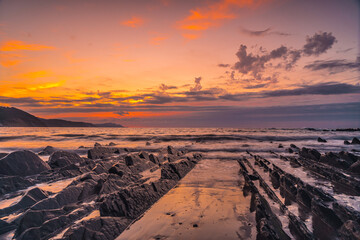Beautiful orange sunset on the beach of Sakoneta and its beautiful Flysch in the town of Deba, At the western end of the Geopark of the Basque Coast, Guipúzcoa. Basque Country