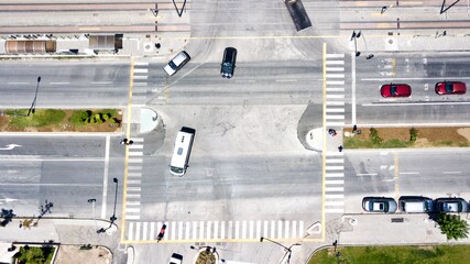 Aerial view of junction with traffic and people on crosswalk.