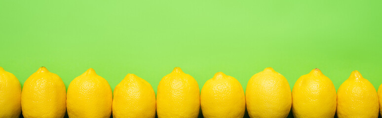 top view of ripe yellow lemons on green background with copy space, panoramic crop