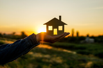 house in hands over beautiful sunset