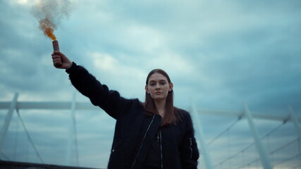 Girl protesting on street with smoke bomb in hand. Woman holding smoke grenade