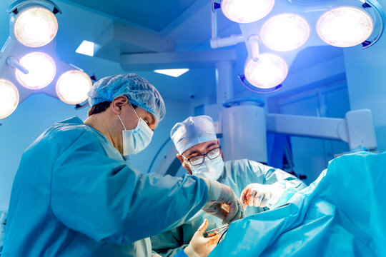 Medical team performing surgical operation in bright modern surgery room. Operating theatre. Modern equipment in clinic. Emergency room.