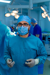 Young handsome surgeon in hospital room. Surgeon in operating room. Protective scrubs and mask.