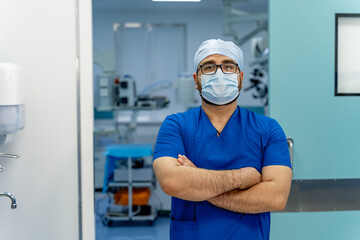 Portrait of young surgeon in scrubs standing in operating theatre. Portrait of male doctor in modern medical room.