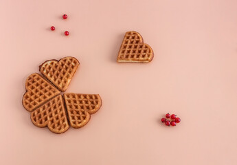 homemade heart-shaped waffles, tea cakes with red currant on a pink background