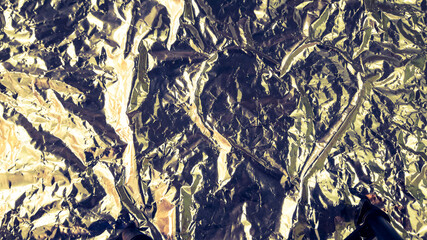 Abstract background. Heart shape in the middle of a crumpled aluminum foil.
