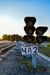 Railway traffic light and rails on the background of the setting sun. Railroad tracks at sunset.