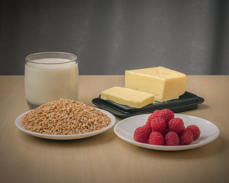 Glass of milk, oat, butter and raspberry on a table