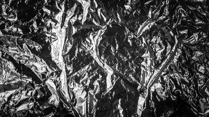 Abstract background. Heart shape in the middle of a crumpled aluminum foil.