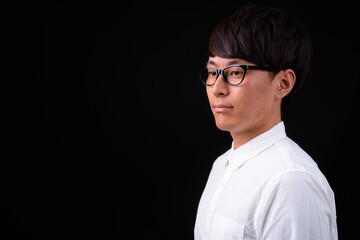 Young handsome Asian businessman against black background