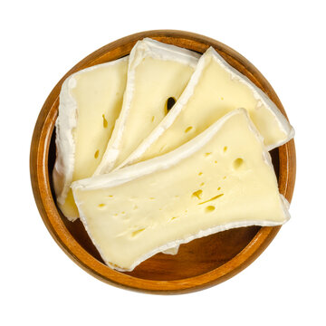 Slices of soft mould cheese in wooden bowl. Moist creamy cheese, made of cow milk, ripened on the surface with a special fungus. Well known as Camembert or Brie. Closeup, from above, macro food photo.