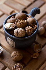 A brown earthenware mug full of nuts. Walnuts and hazelnuts in a high dish