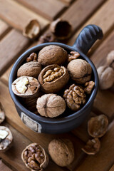 A brown earthenware mug full of nuts. Walnuts and hazelnuts in a high dish
