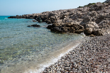 Fototapeta na wymiar Acqua cristallina spiaggia con sassi di Kos. Grecia