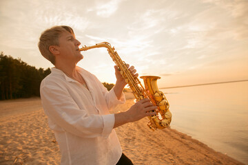 The musician plays the saxophone on a Golden sunset 
