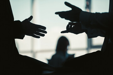 Hands silhouettes of business people standing opposite the window in office. Close up shot. Tinted...