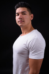 Young handsome multi ethnic man against black background