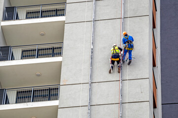 Two workers hang on the building and doing electrical installations