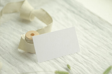 Summer stationery mockup scene with herbs, vintage spool of cotton braid, on a light background. Mockup card for greeting card or wedding invitation in minimal style.