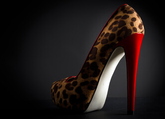 Leopard high heel shoe with red heel on black background