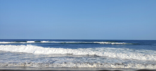 Big breaking ocean wave on a sandy beach on the Pacific Ocean.