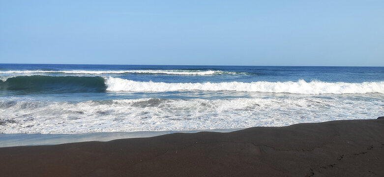 Big breaking ocean wave on a sandy beach on the Pacific Ocean.