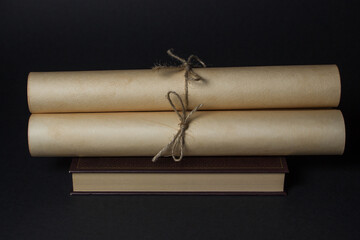 Old scrolls lie on the book. Education concept. Ancient knowledge. Photo on black background