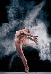 Fototapeta na wymiar dancing girl in flour (powder). Black studio. Ballet dance.
