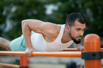 A man does push-UPS on the bars on the street