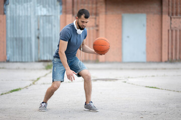 Naklejka premium Man plays basketball in the street yard during the day