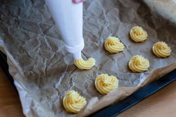 Bignè alla panna all'italiana. Profiteroles al cioccolato fondente. Preparazione a mano prima della cottura al forno.