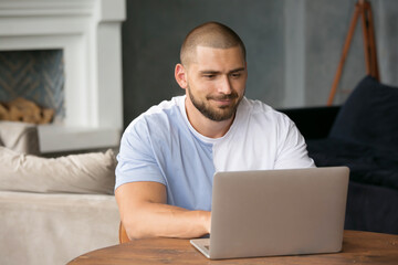 cute young man with a beard at a laptop, talking with loved ones and smiling