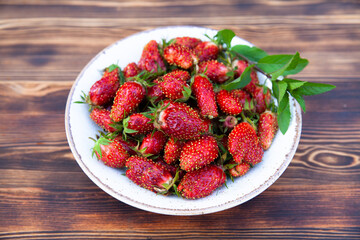 bowl with ripe strawberries and mint on dark wooden table