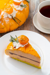 A slice orange souffle cake with tea and a whole torte on background