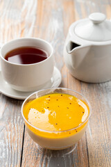 Mango panna cotta with cream and tropical taste on wooden table in a take away plastic cup