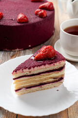 Close up of red velvet strawberry cake on white elegant plate, layered strawberry torte with beautiful purple icing