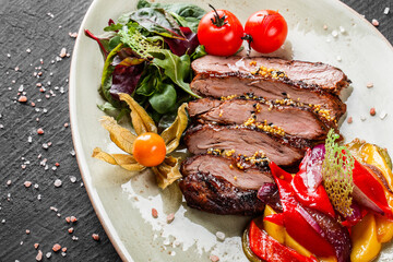 Grilled veal steak with salad and vegetables in plate on dark stone background. Hot Meat Dishes, top view