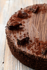 A whole chocolate birthday cake with cocoa powder on top, half is visible, close up