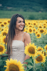 
a young beautiful smiling girl posing in a field of sunflowers