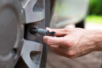 Closeup of man hand taking off valve. Checking tyre pressure.