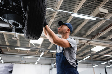 low angle view of technician touching car tire in service station