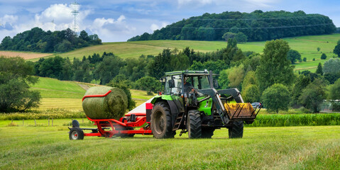 Tractor loading bales of hay - obrazy, fototapety, plakaty
