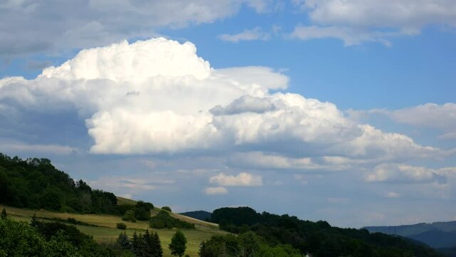 Timelapse - Massive clouds in the distance over the hilly landscape