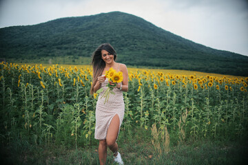 
a young beautiful girl in a sunflower field with a bouquet of sunflowers