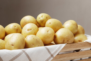 Wooden box full of young potato on a wooden table with place for text.