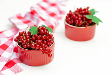 Red currant berries in a cocotte bowl on a white plate with a kitchen towel. Natural vitamins concept. Flat lay.