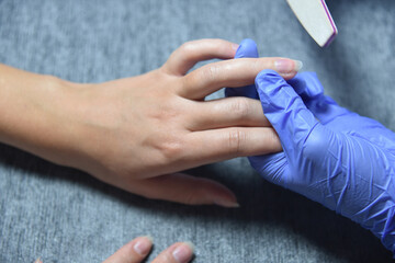 A manicure procedure in the beauty saloon, transparent nail polish 
