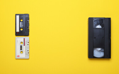 Old audio cassettes and video cassette on a yellow background.Creative concept in retro style, 80s....